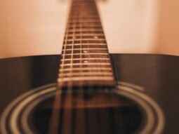 close-up photograph of black dreadnought acoustic guitar